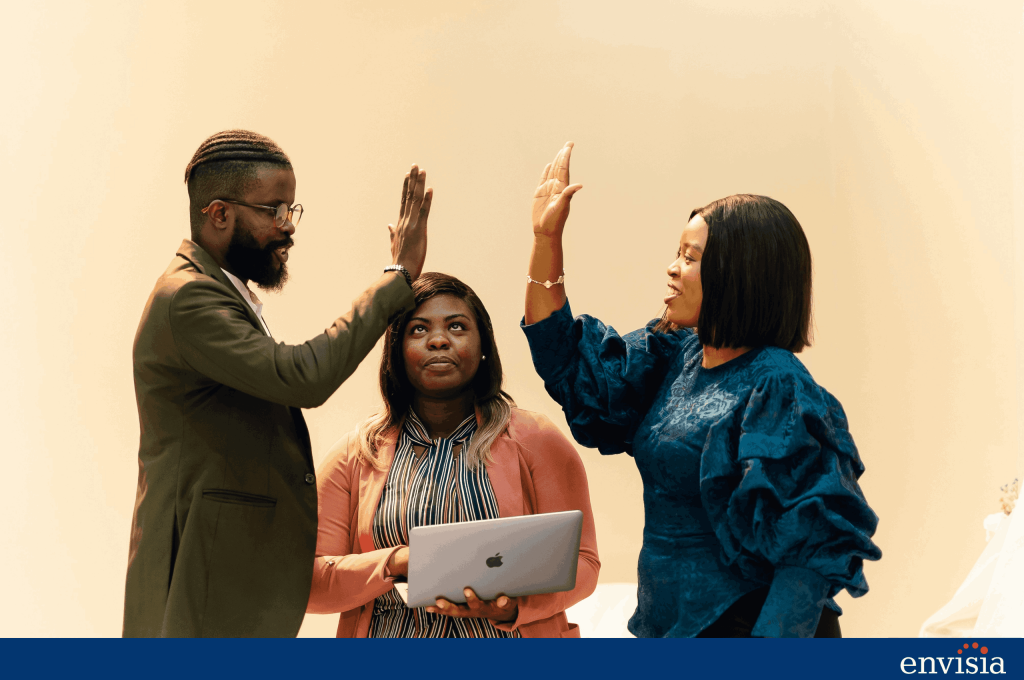 Three professionals celebrating with a high five, representing collaboration, confidence, and what to expect from executive coaching.